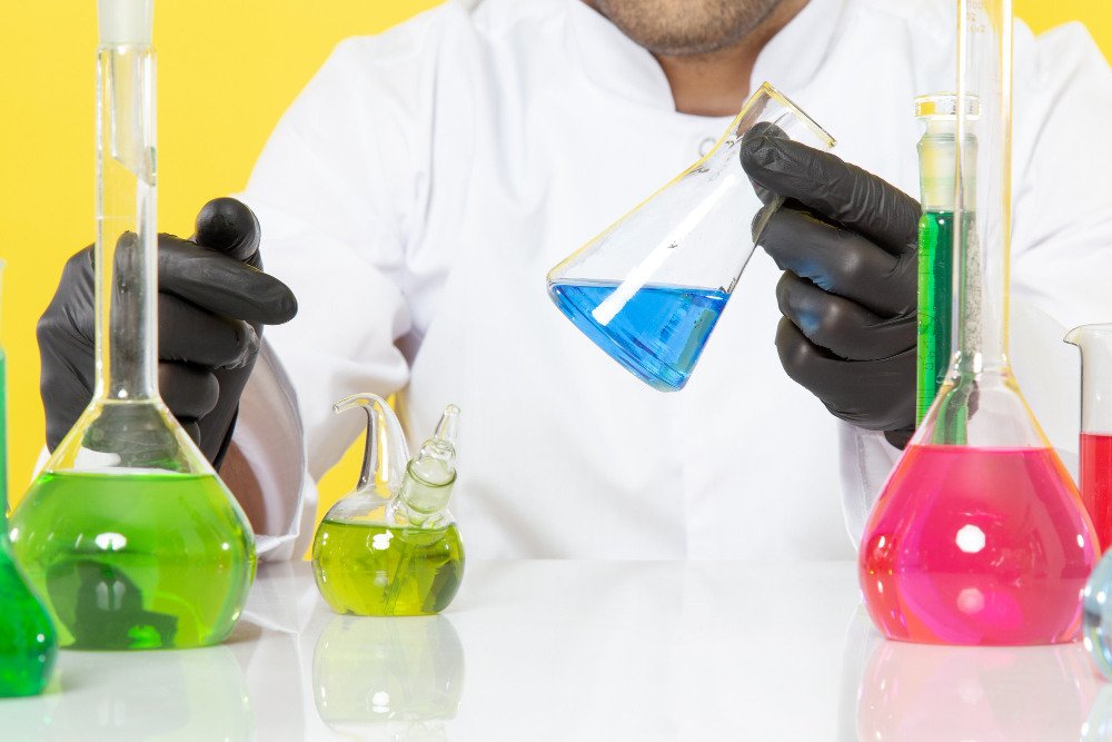 Laboratory technician holding a beaker of blue chemical solution during chemical testing in Qatar.