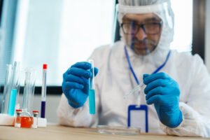 Laboratory professional conducting chemical testing using test tubes and a pipette.