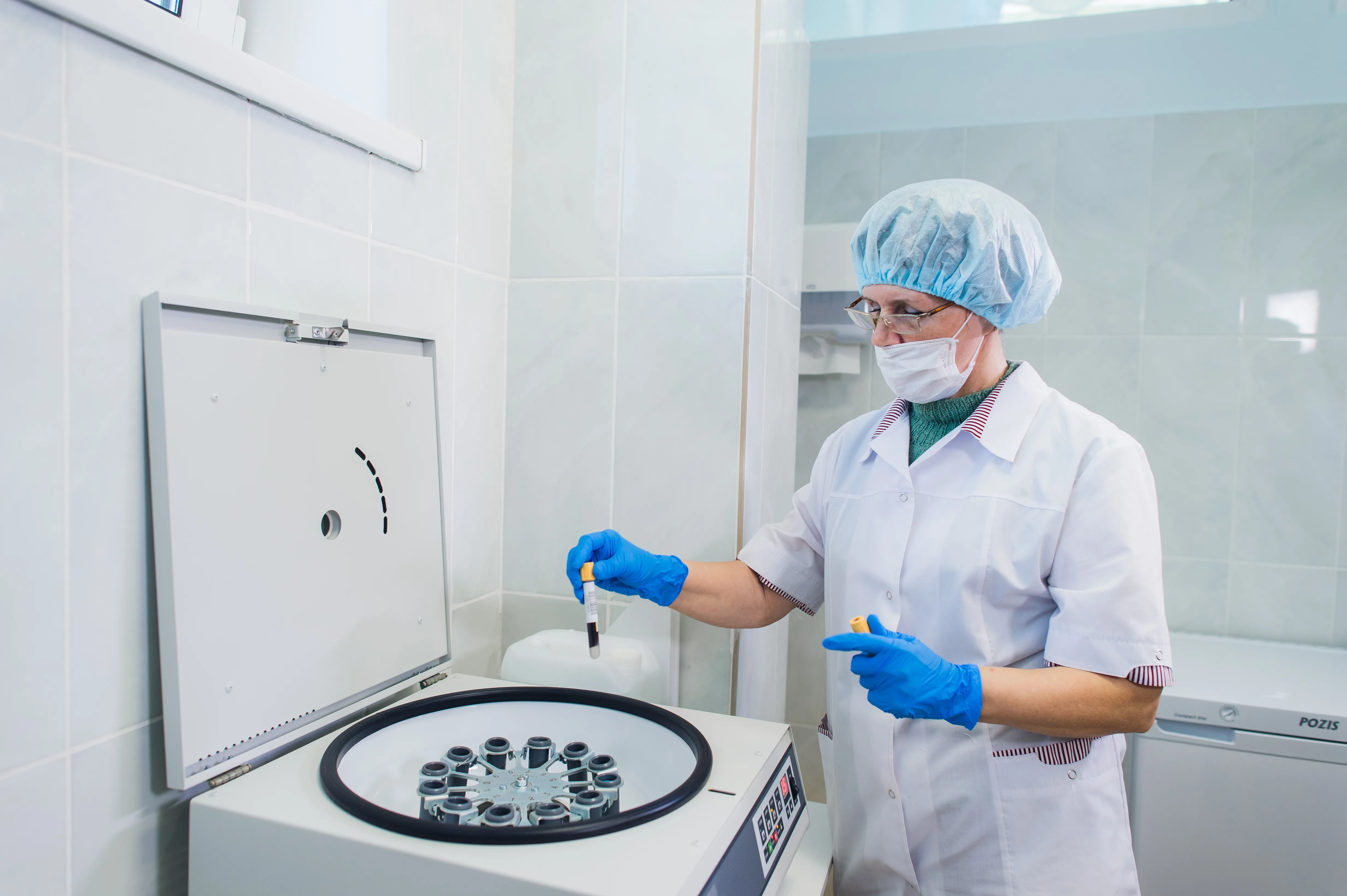 gloved hand holding test tube by river