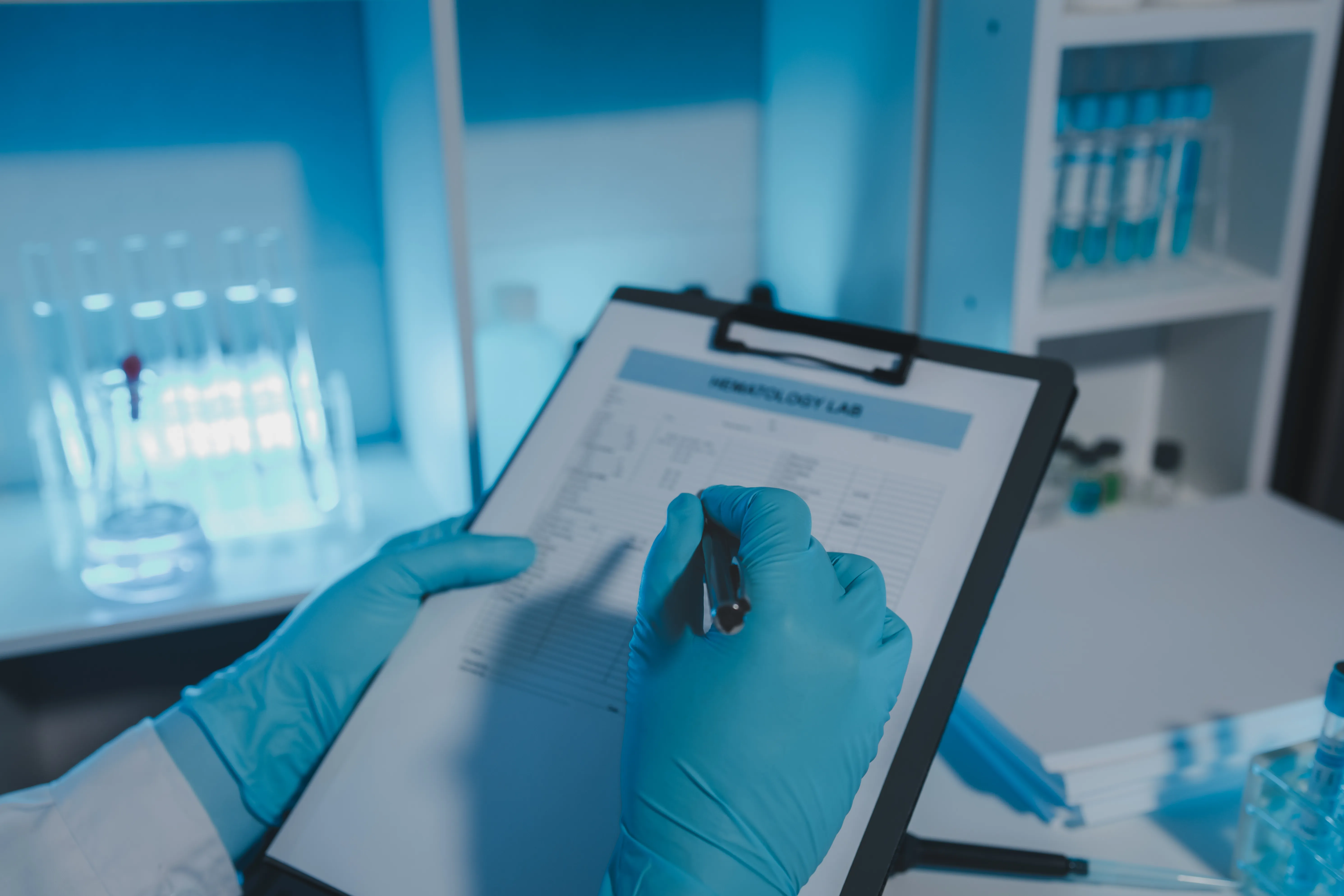 gloved hand holding test tube by river