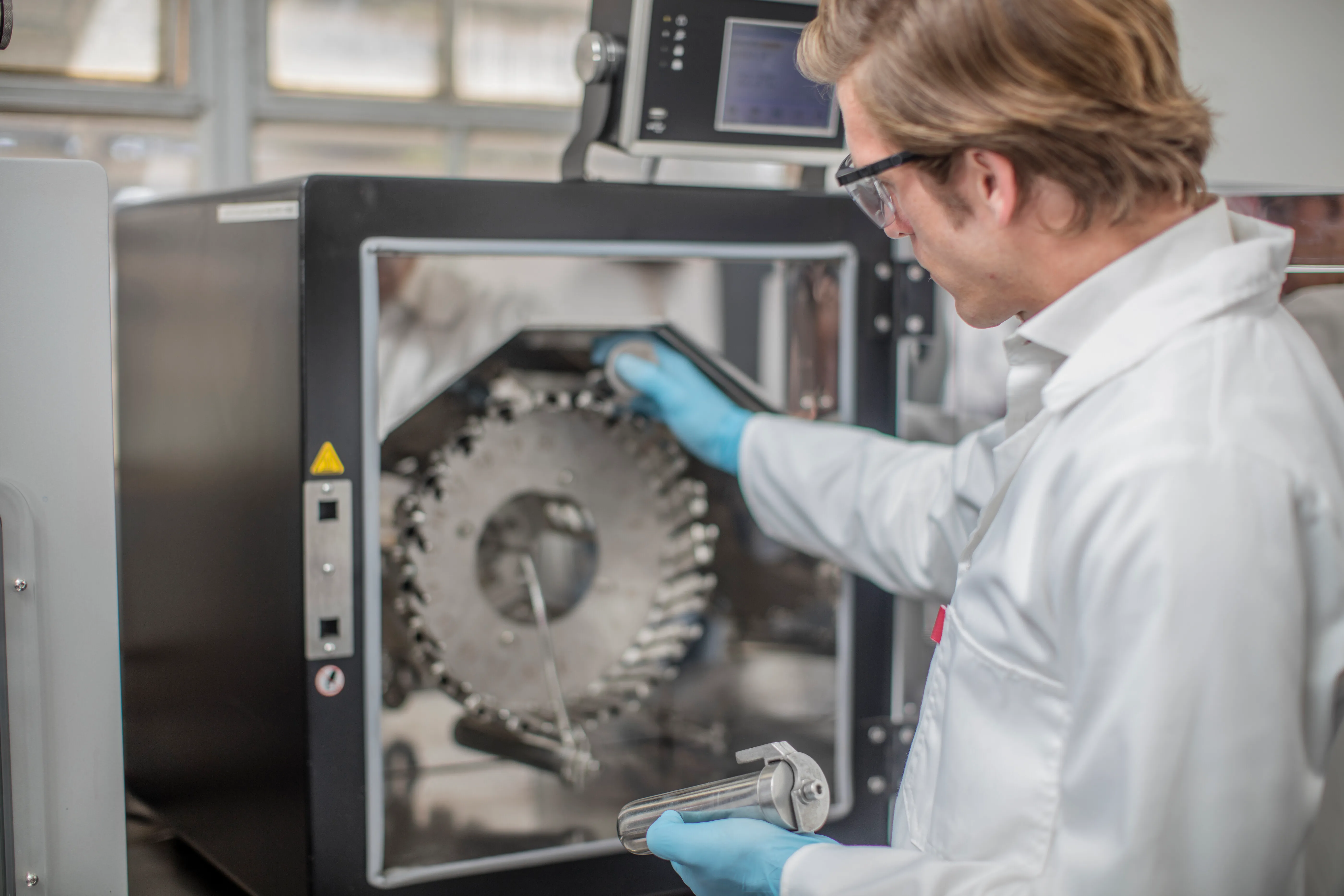 gloved hand holding test tube by river